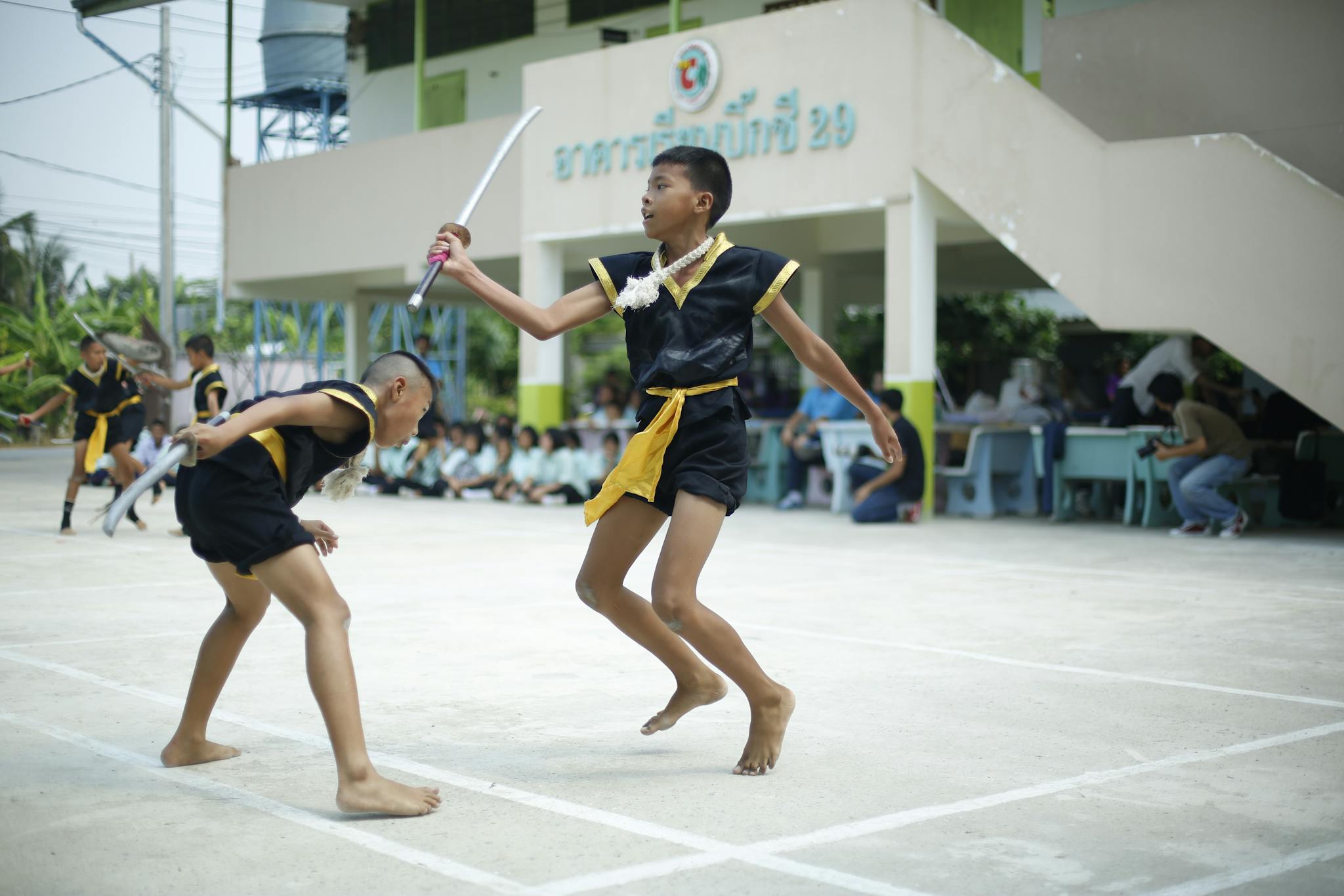 Boys practicing traditional Thai martial arts at an outdoor training session.